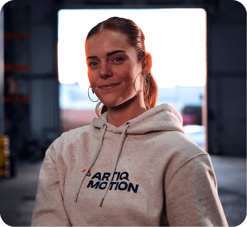 Lachende vrouw met Artiq Motion hoodie in industriële omgeving Lachende vrouw met Artiq Motion hoodie in industriële omgeving